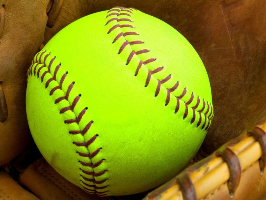 a bright yellow softball inside a softball glove