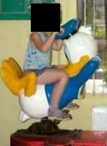 Young child riding on an odd-looking Donald Duck ride