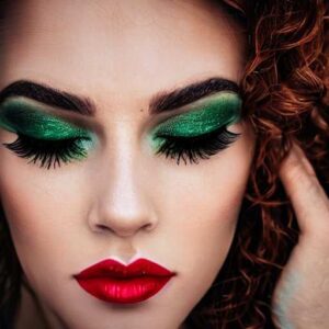 close-up image of a woman's face with green eyeshadow and red lipstick