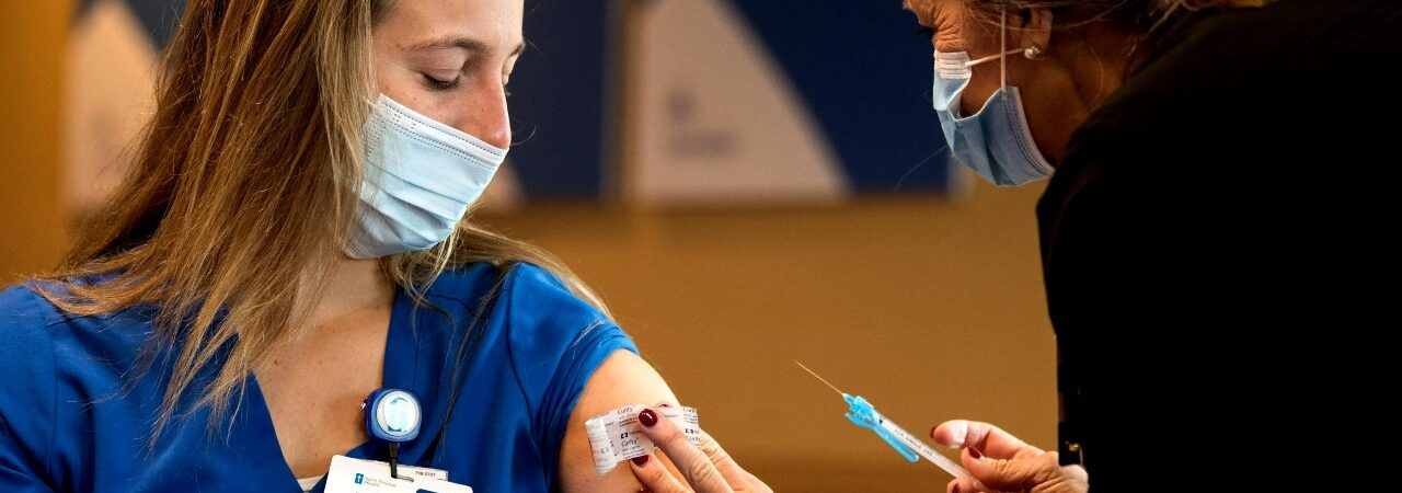 Health care provider gives a woman a vaccine.