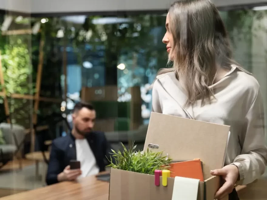 A young female marketer carrying a cardboard box as she leaves the office on her last day of work